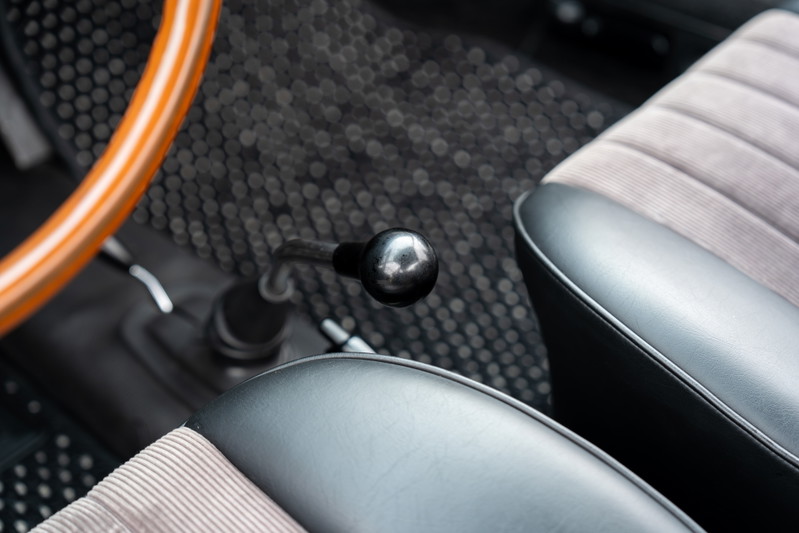 Interior of a 1965 blue Porsche 912, showing the wooden steering wheel, shifter, and corduroy seats.