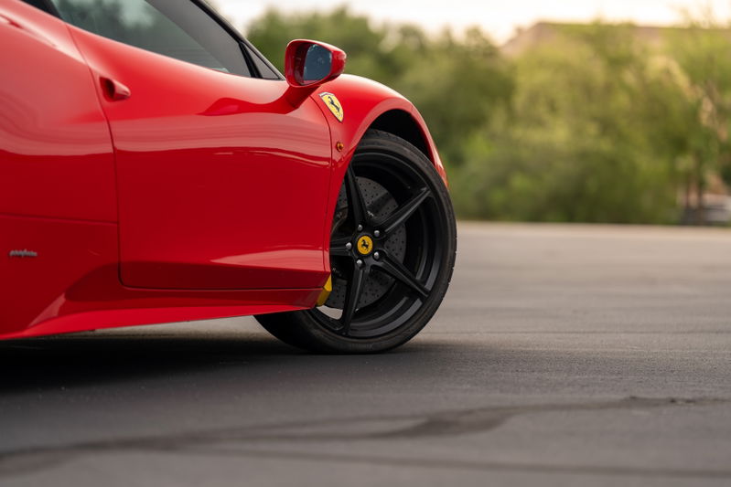 Red Ferrari 458 Italia, side profile, black five-spoke rims, yellow brake calipers.