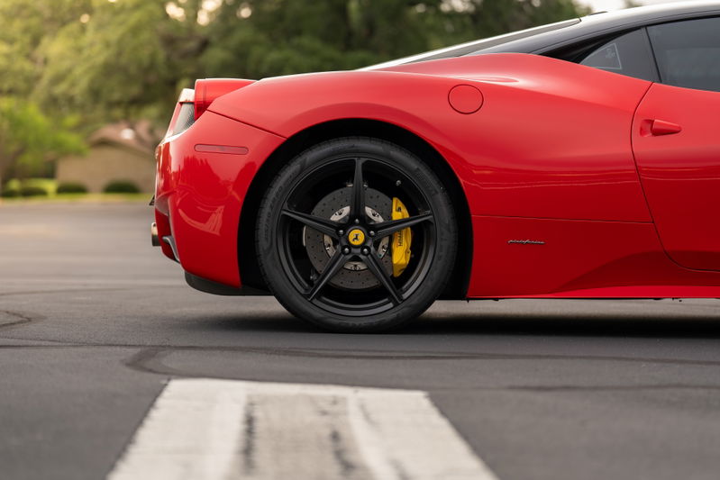 Red Ferrari 458 Italia rear wheel with black 5-spoke rims and yellow brake calipers.