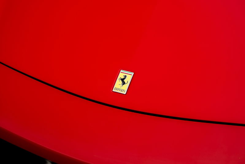 Close-up of the Ferrari Prancing Horse badge on the hood of a red Ferrari 458 Italia.
