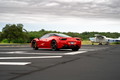 Red Ferrari 458 Italia on tarmac, black rims, dark tinted windows.