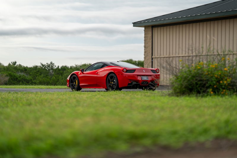 Rear view of a red Ferrari 458 Italia with black rims and yellow brake calipers.