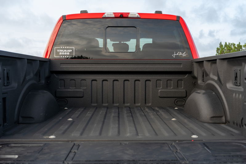 Red Ford F-150 Roush bed with "TRUMP 2020" decal on rear window.
