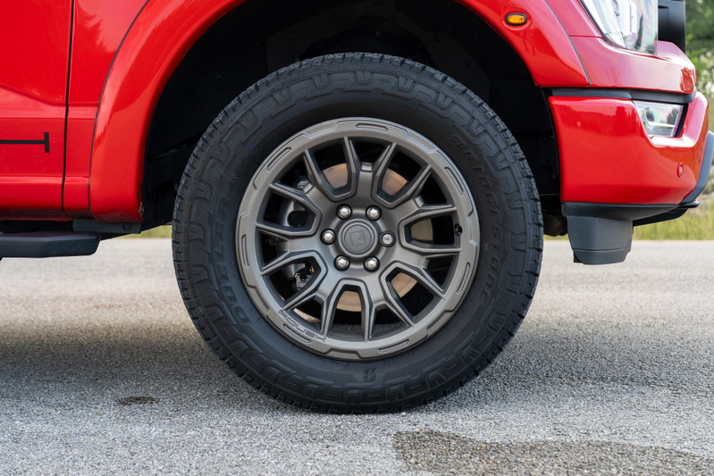 Red 2022 Ford F-150 Roush with gunmetal gray, multi-spoke rims and aggressive all-terrain tires.
