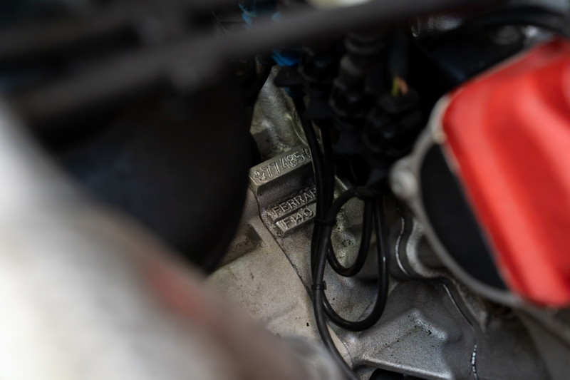 Close-up of the "FERRARI F140" engine block stamping in a Rosso Corsa Enzo.