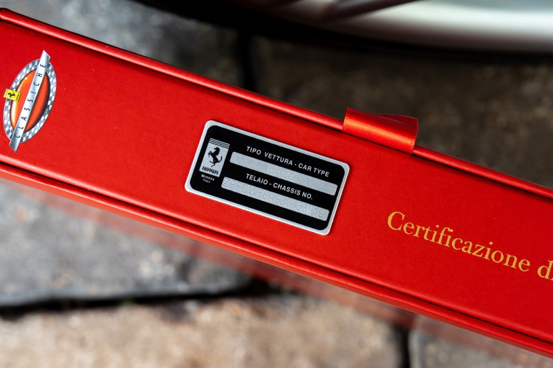 Close-up of red Ferrari Enzo's Classiche certification plate and chassis number.