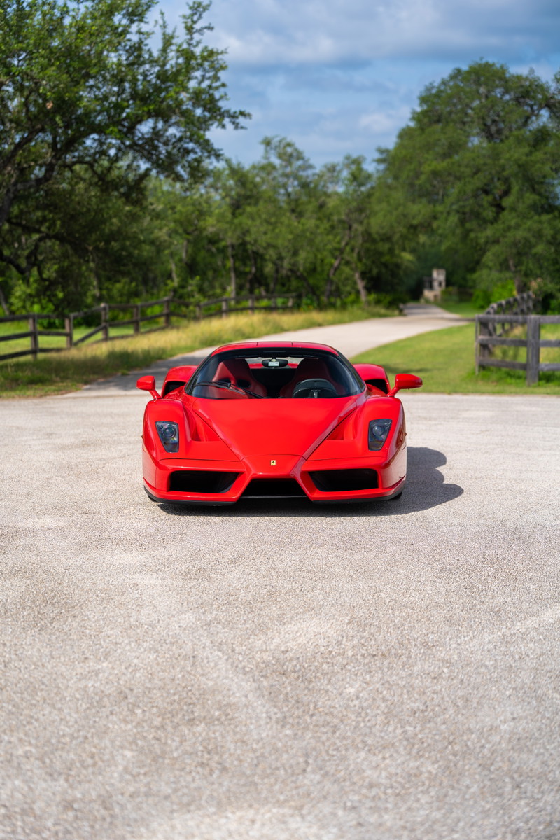 Front view of a red 2003 Ferrari Enzo with black trim and tinted headlights.
