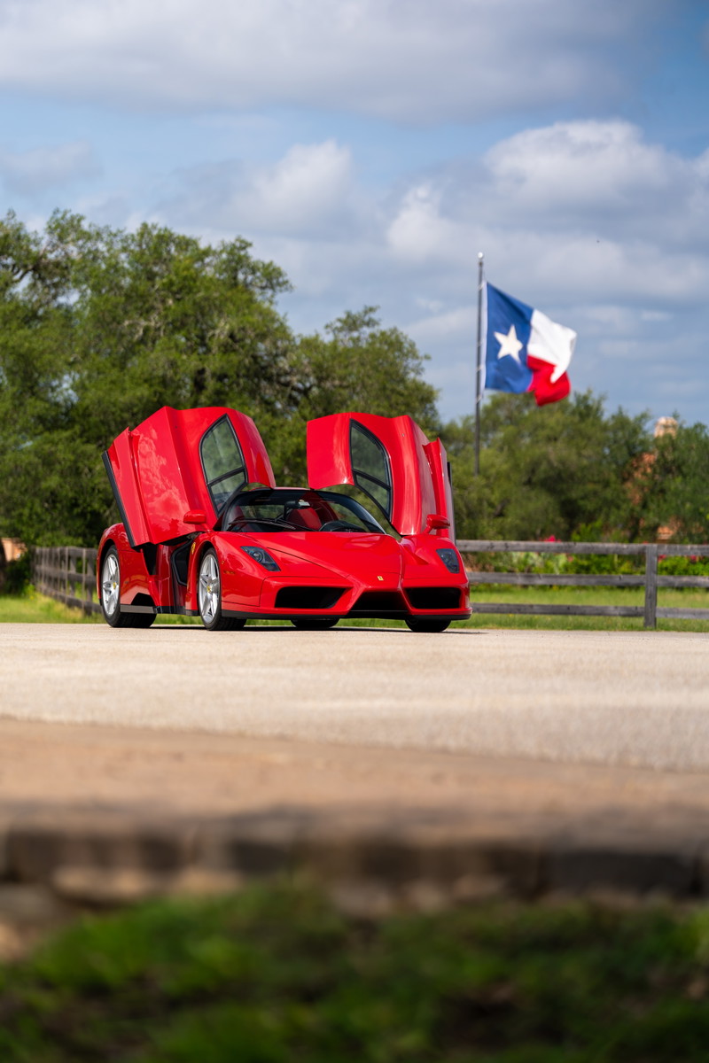 Rosso Corsa 2003 Ferrari Enzo with butterfly doors open, Texas flag in background.