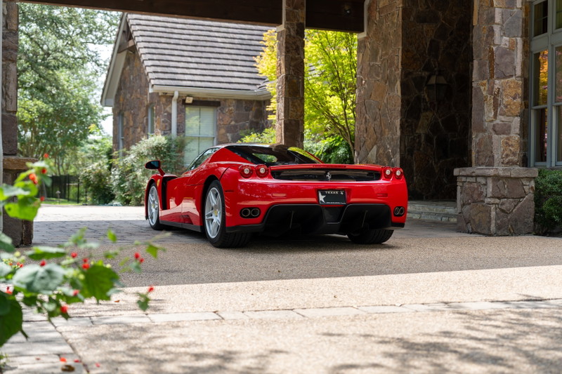 Rosso Corsa Ferrari Enzo with silver rims, parked under a stone portico.