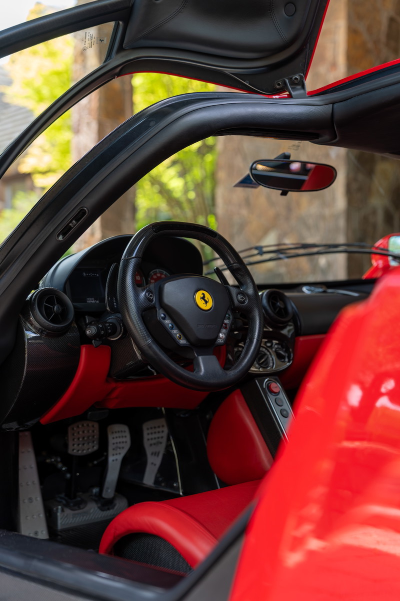Rosso Corsa 2003 Ferrari Enzo interior with red leather trim, carbon fiber accents, and aluminum pedals.