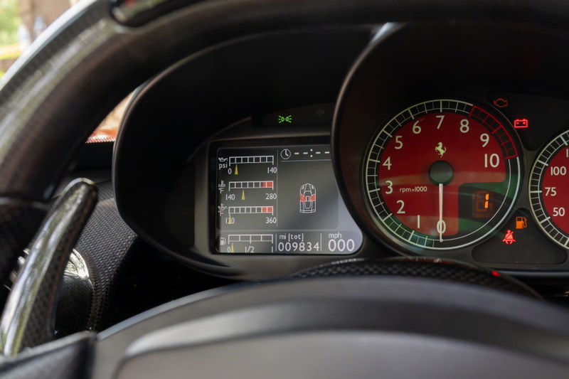 Ferrari Enzo dashboard: Red tachometer, digital display, carbon fiber trim, paddle shifters.