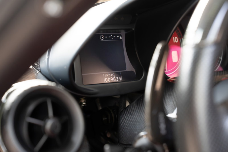 Ferrari Enzo dashboard shows digital display with 98,834 miles. Red tachometer visible.