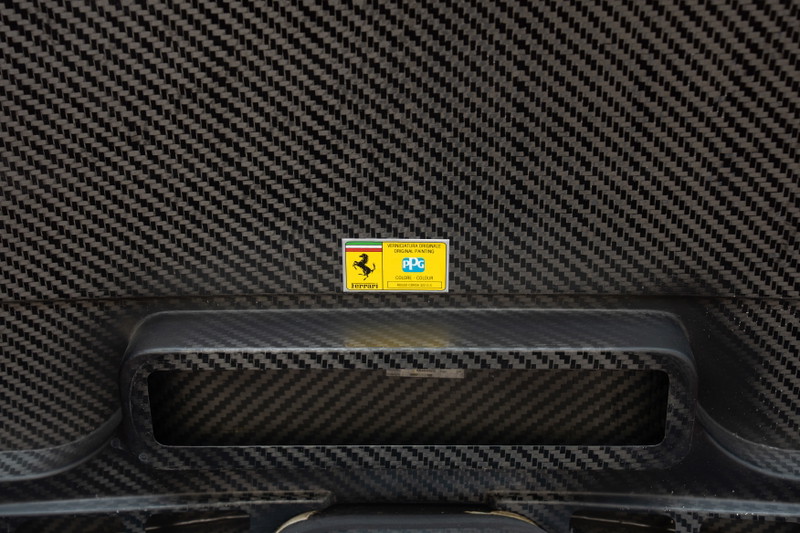 Close-up of a yellow sticker on the carbon fiber weave of a 2003 Ferrari Enzo.