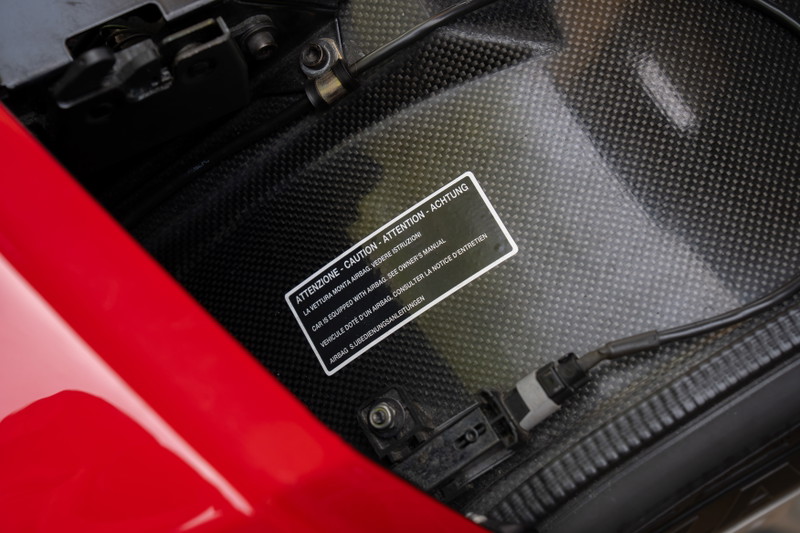 Close up of a red Ferrari Enzo carbon fiber interior with an airbag warning sticker.