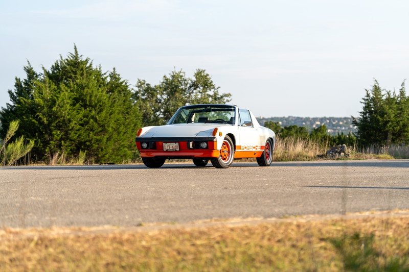 1974 Porsche 914 Can-Am Le with orange trim and rims, parked on a road.