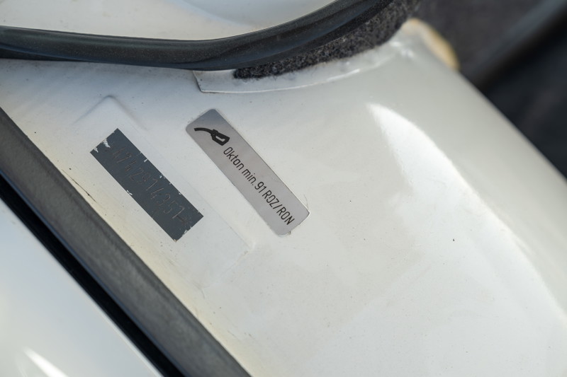 Close-up of white 1974 Porsche 914 fuel door sticker indicating minimum 91 octane fuel.