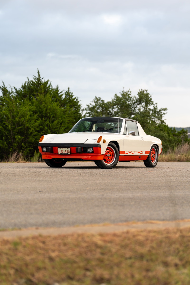 White 1974 Porsche 914 Can-Am with orange racing livery, front bumper, and rims.