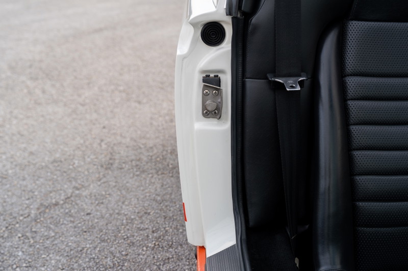 Close up of the door latch and black perforated seat in a white 1974 Porsche 914.